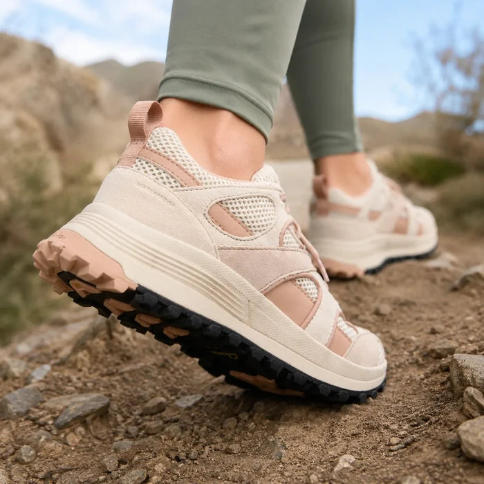 Women's sand trail sneaker close-up on rocky path, treaded rubber outsole
