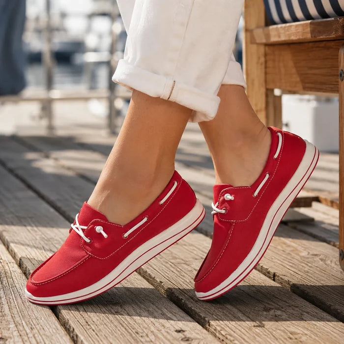Close-up of cherry red canvas loafers with white laces and striped midsole