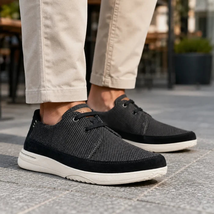 Men's black lace-up sneakers with textured mesh upper and tan collar trim, white sole