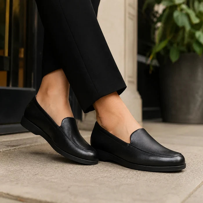 Black leather slip-on loafers with low flat sole on pavement.