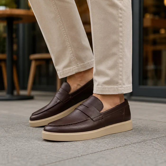 Men's brown leather loafers on pavement, slip-on design with light beige soles