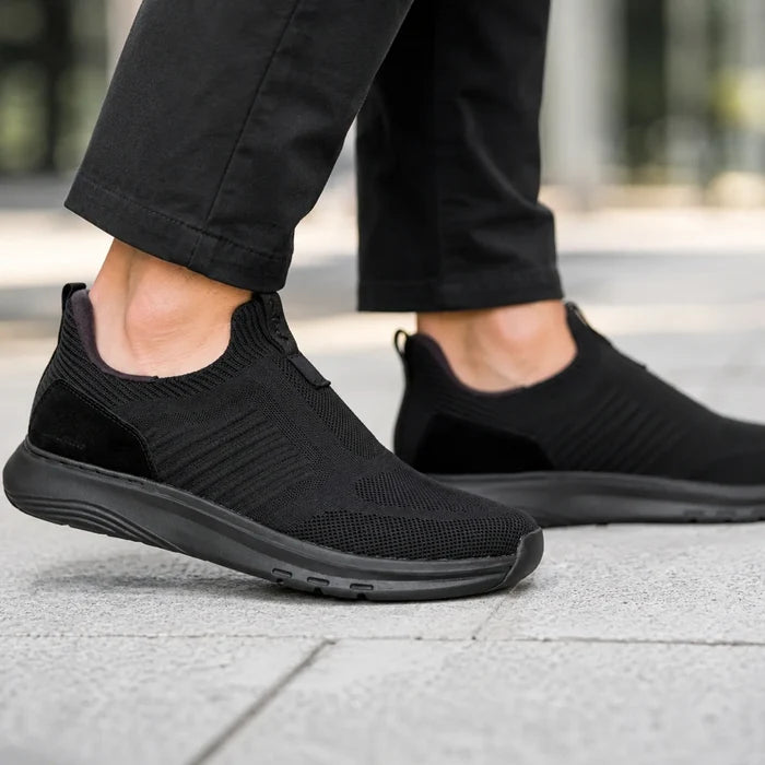 Men's black slip-on walking sneakers on feet with knit uppers and rubber outsole