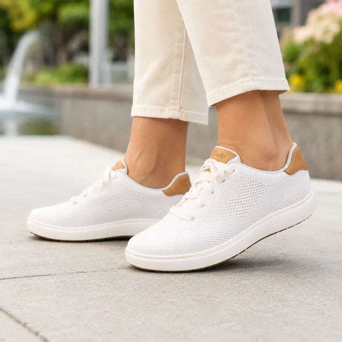 Pair of women's white knit lace-up walking sneakers with brown heel accents