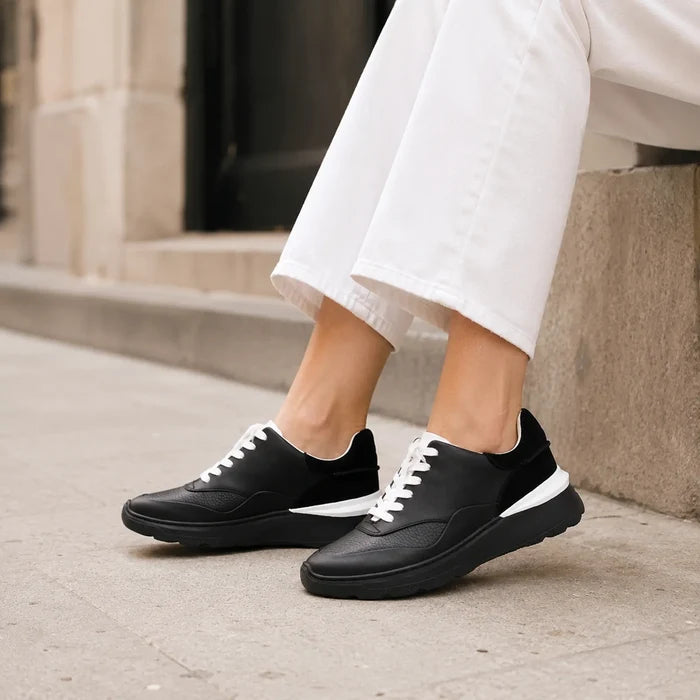 Women's black leather sneakers with white lace-up front and thick cushioned sole