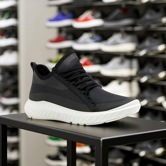 Black sneaker with diagonal strap, lace-up front, and white cushioned sole