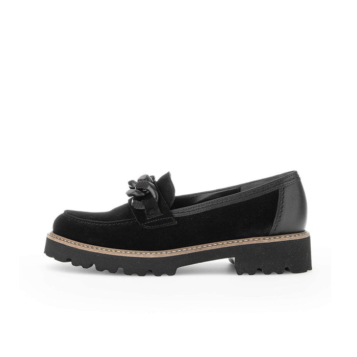 Black loafer profile with tied vamp detail and chunky lug sole, tan edge stitching.