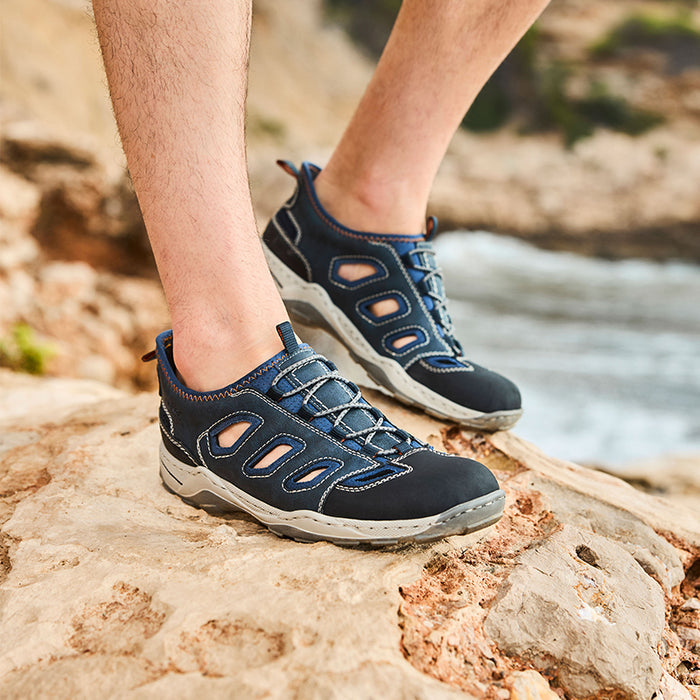 Men's blue lace-up outdoor sandals on rocky ground, side cutouts and cushioned sole