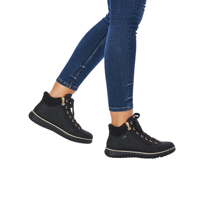 Black lace-up ankle boots worn with blue jeans, textured rubber sole
