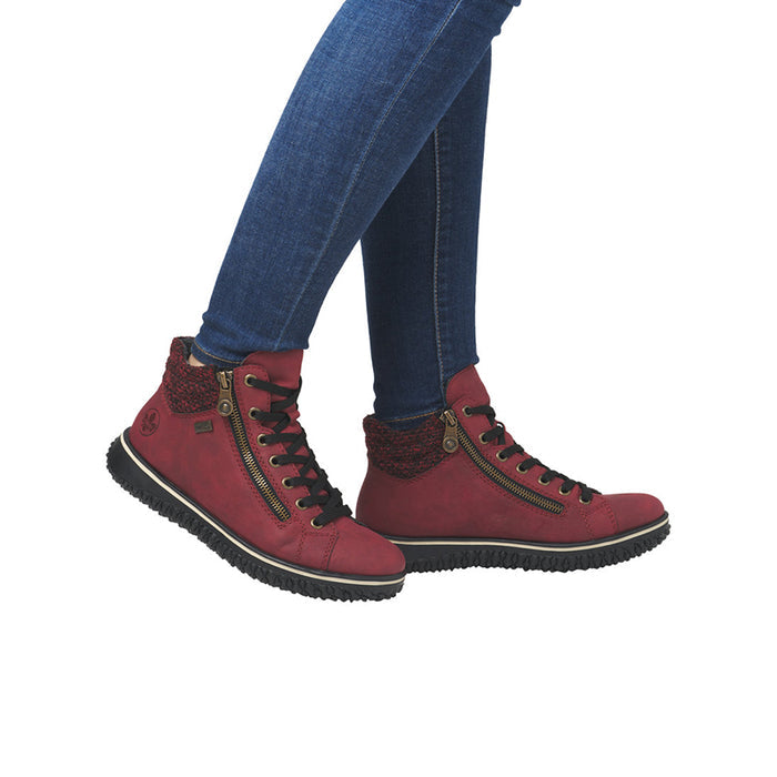 Red lace-up ankle boots worn with blue jeans, textured rubber sole