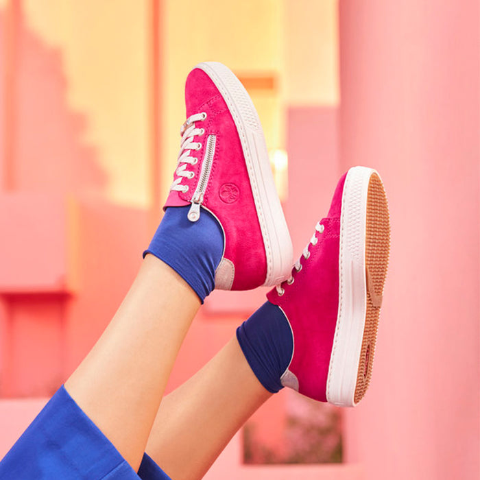 Magenta sneakers on feet with white laces and side zip detail